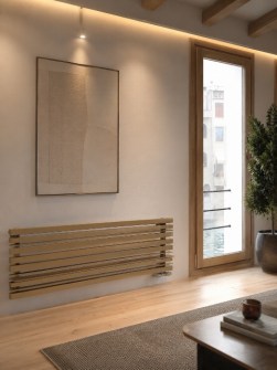 Beige designer horizontal radiator in a modern interior with light wood flooring.